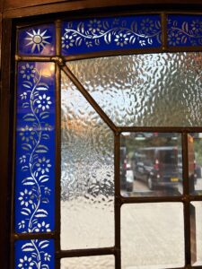 Close-up of blue glass with a white floral pattern in a leaded door panel