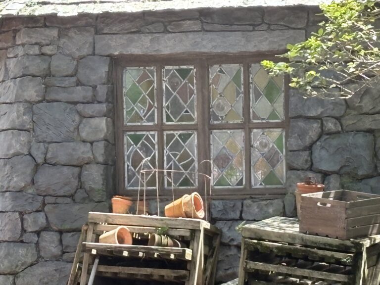 Casement window with coloured diamond leaded lights in stone wall