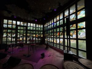 Corner windows with a tree in coloured glass seen from across the stage
