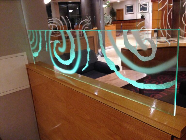 Curved glass counter screen with carved swirls
