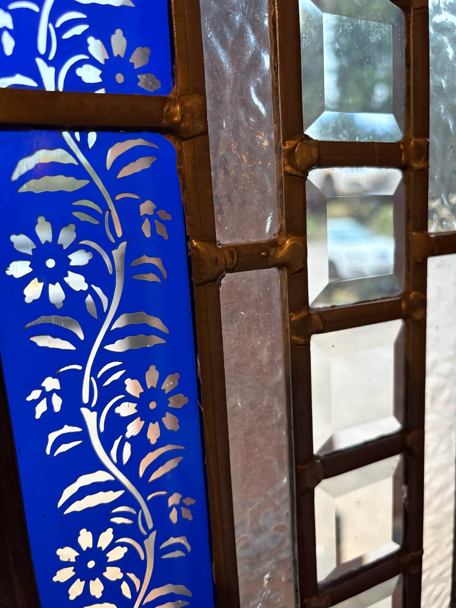 Close view of a blue floral border beside clear bevelled squares set in lead