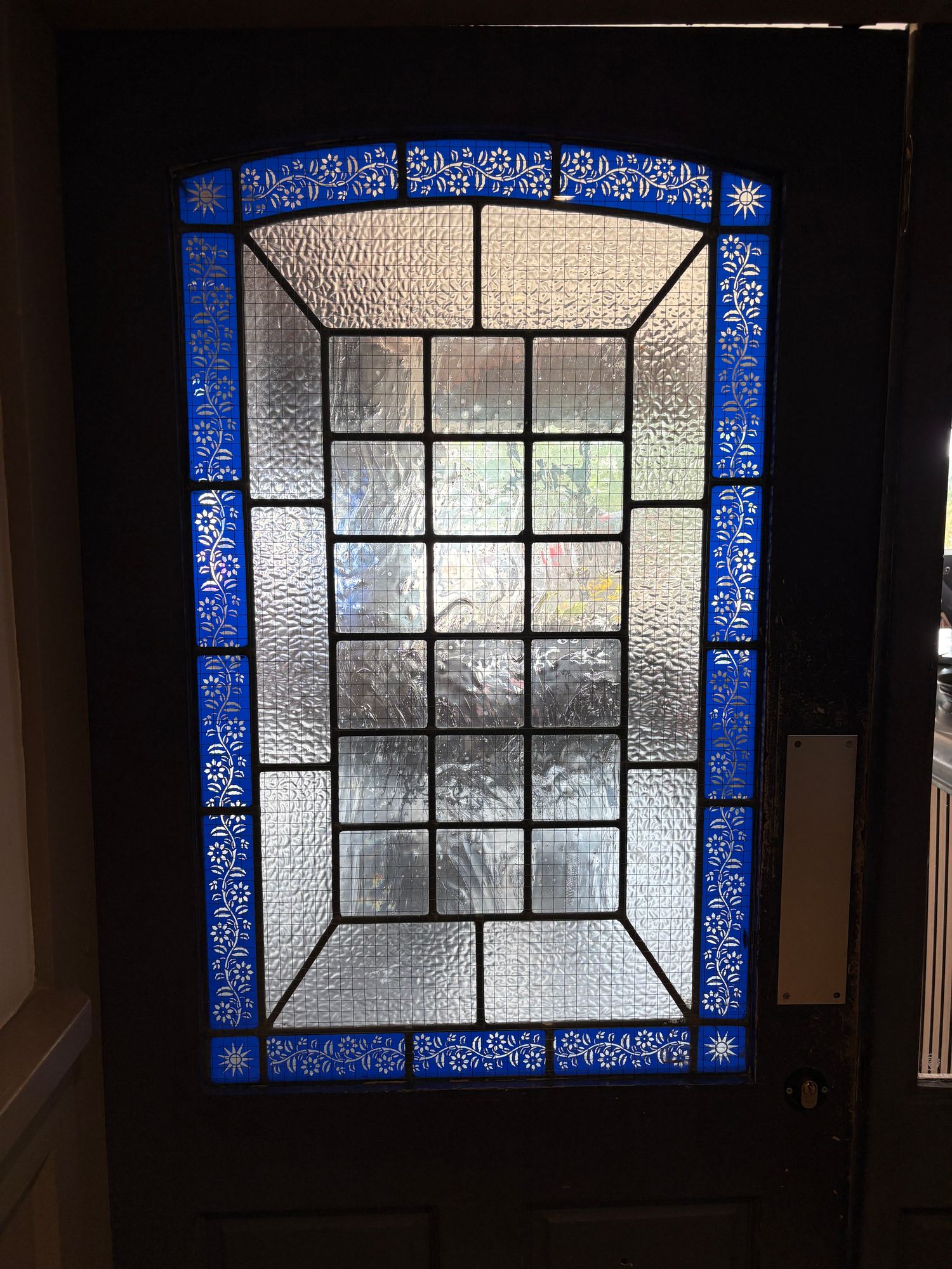 Door window with a blue floral border around clear bevelled squares and textured glass