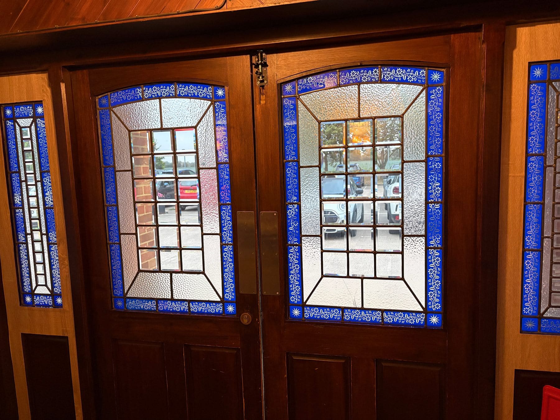 Pair of wooden entrance doors with blue-bordered bevelled glass windows and tall narrow side windows
