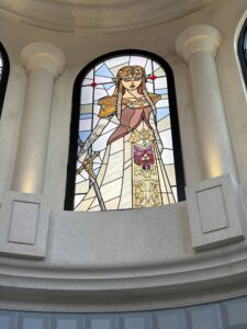 Arched window with a princess in a long gown and golden crown in leaded stained glass
