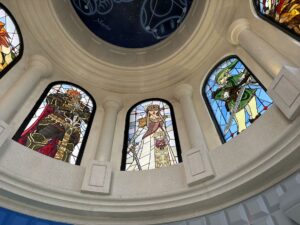 Three arched dome windows with characters in leaded stained glass