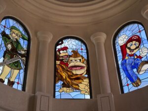 Three arched dome windows seen closer with characters in leaded stained glass