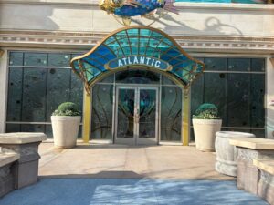Restaurant entrance with a curved blue-green glass canopy lettered Atlantic and dark textured glazing