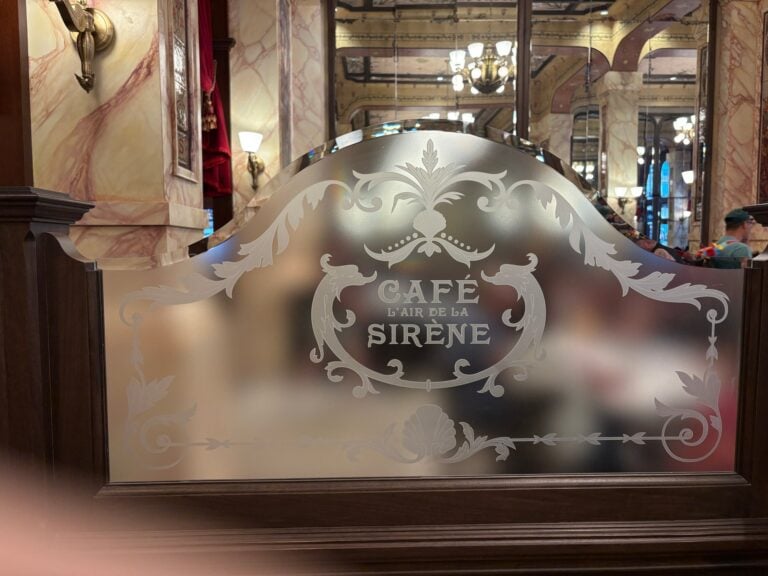 Etched glass panel with scrolls, shells and cafe lettering in a marble-lined room