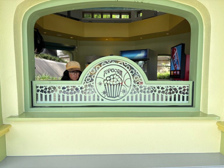 Kiosk serving window with an etched glass panel showing a popcorn tub and scrollwork