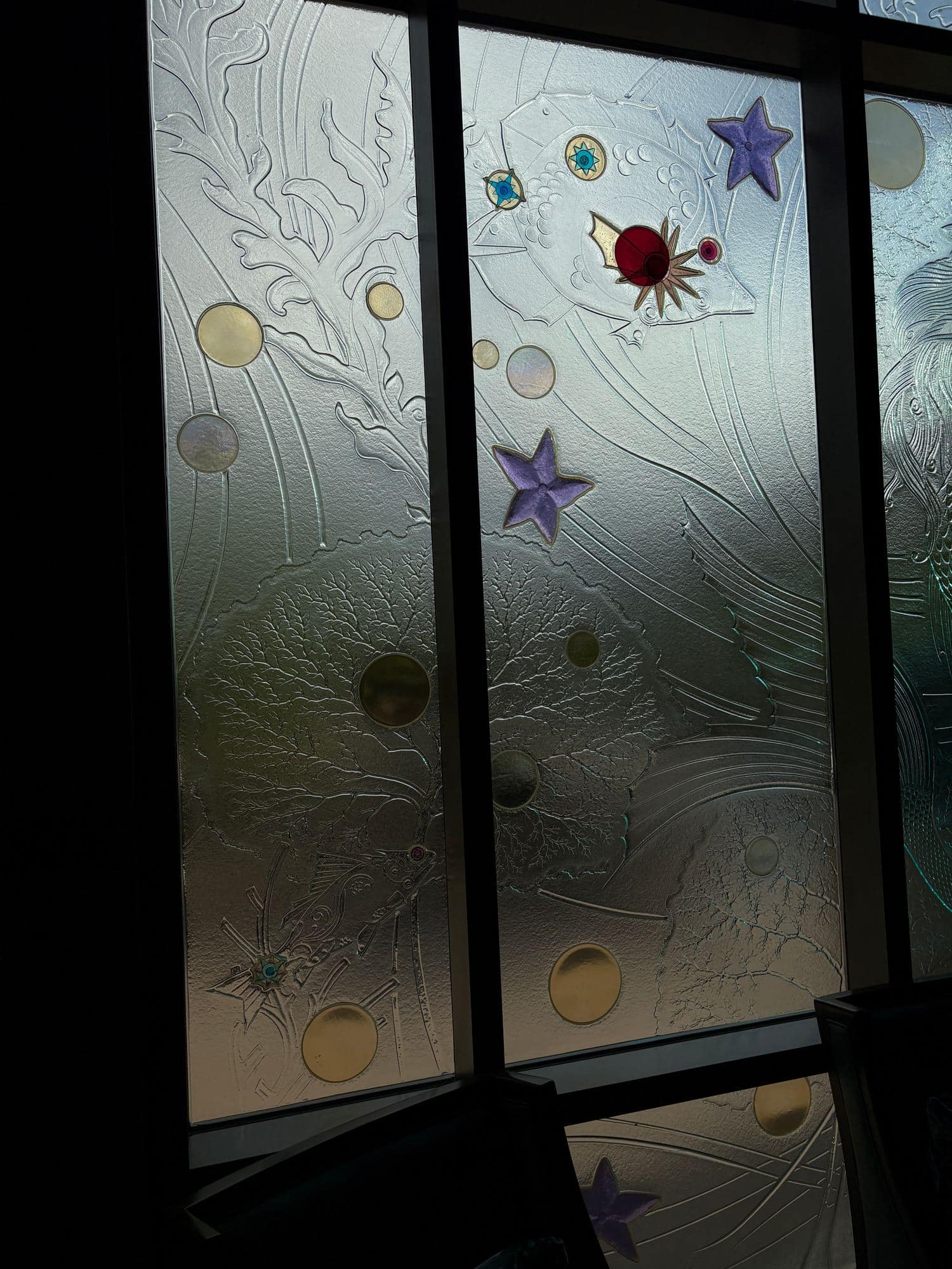 Close view of frosted textured glass with sea-life relief and coloured glass jewels