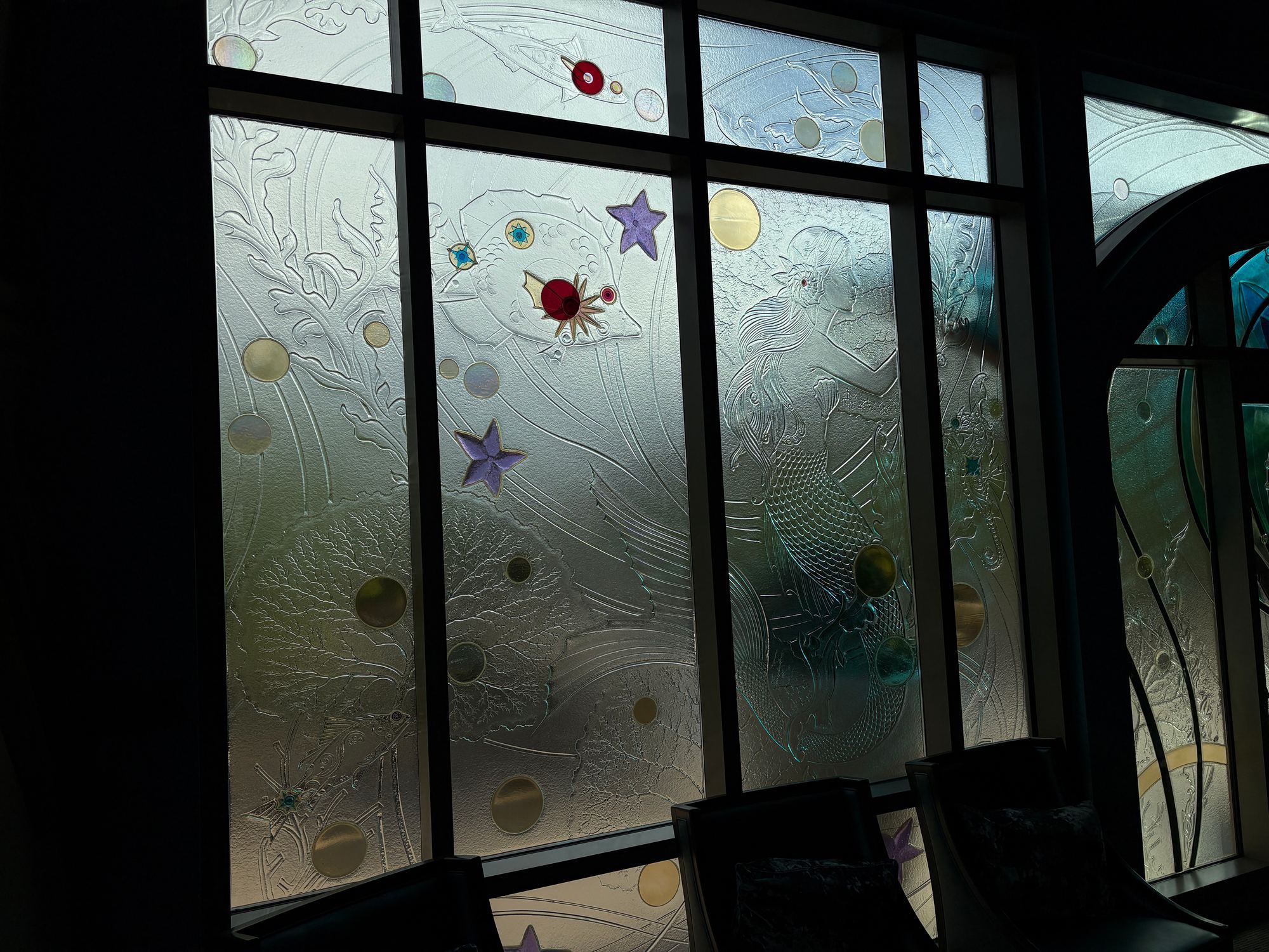 Windows of frosted textured glass with sea-life relief, stars, bubbles and coloured glass jewels