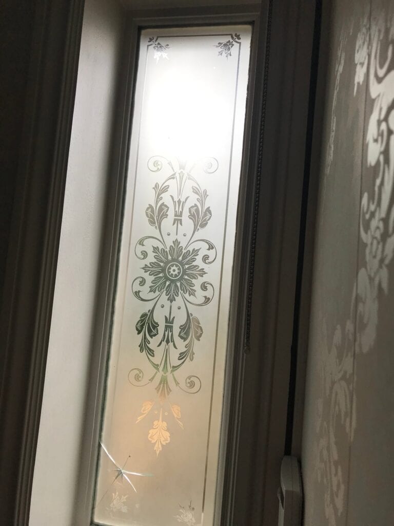 Narrow etched glass door panel with a central rosette and floral scrolls