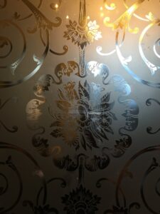 Etched glass panel with central flower and scrolls