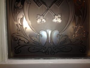 Etched glass panel with crossed keys and scrolling leaves