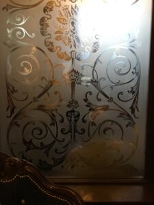 Etched glass panel with scrolls and flower heads