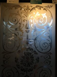 Etched glass panel with scrolls and flower heads bright reflection