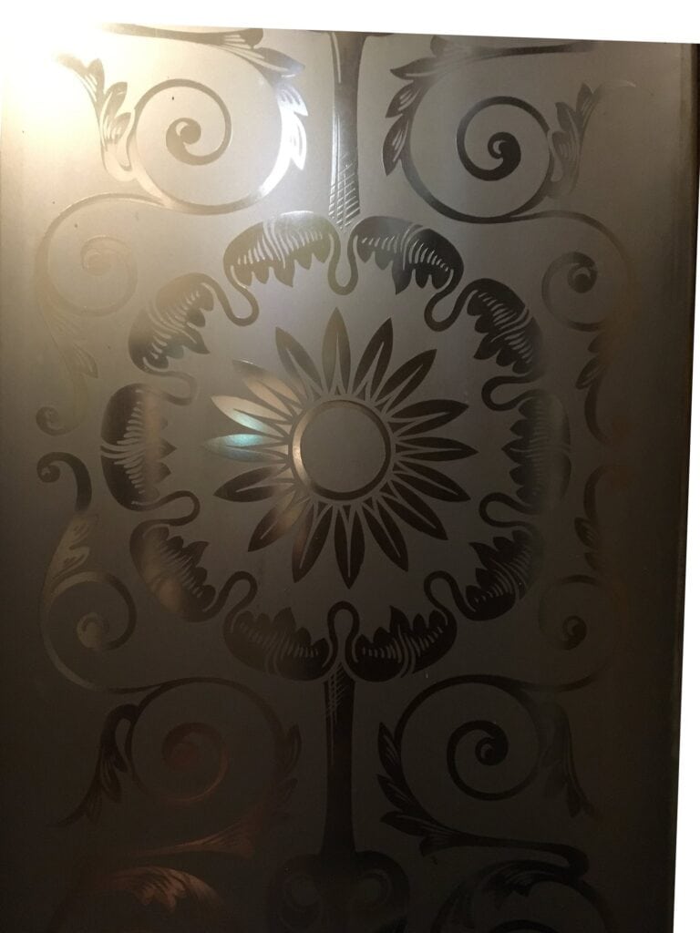 Etched glass panel with sunburst flower and scrolls