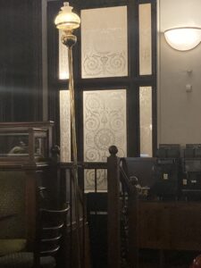 Etched window panels beside a staircase and lamp