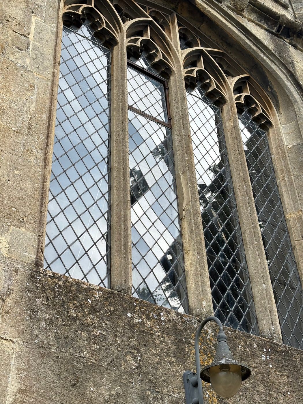 Outside of a church window with diamond quarries and stone tracery, Chippenham