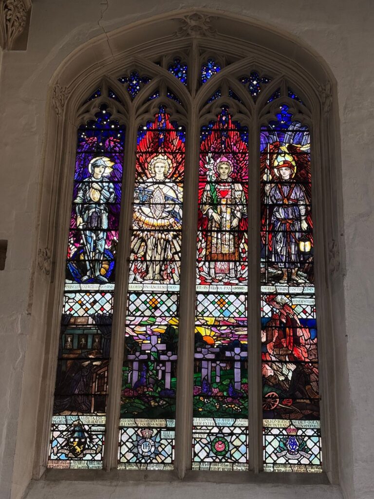 Four-light church window with figures above a war scene and heraldic badges, Chippenham