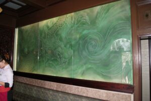 Green glass wall with carved dragon and foliage wide view