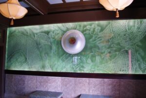 Green glass wall with carved panel and wall light