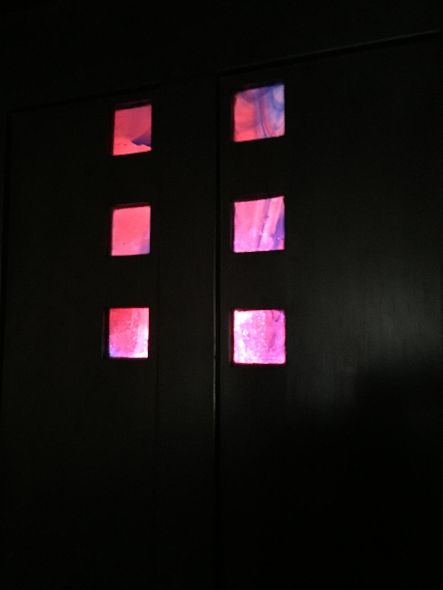 Small squares of red and pink glass set into dark panelling at Hill House