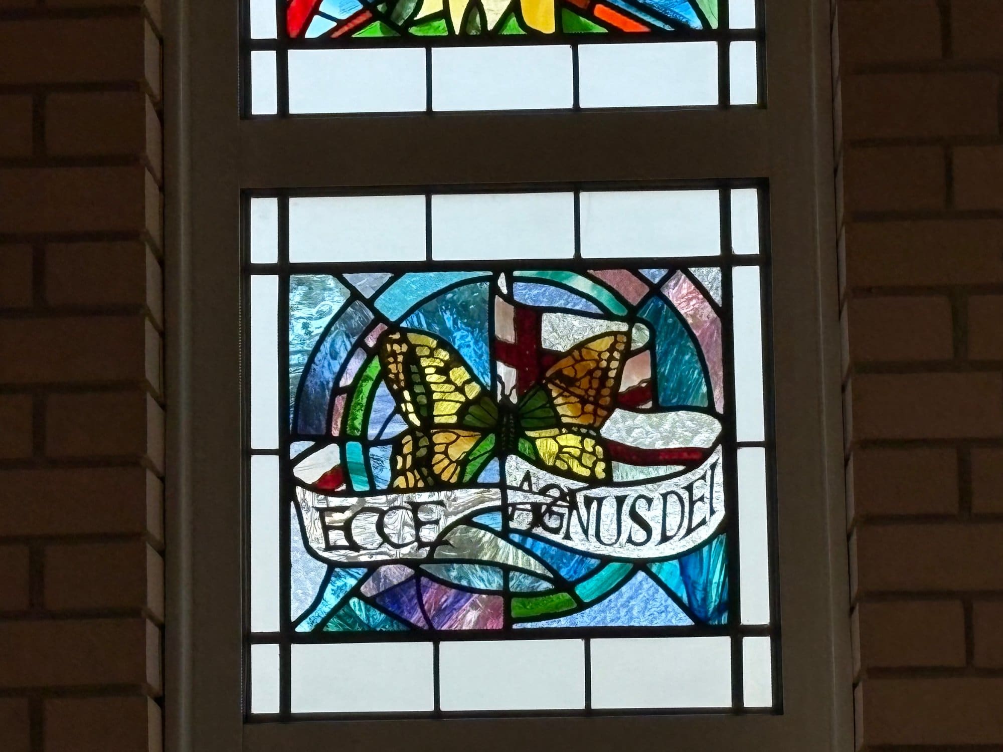 Stained glass panel with a butterfly and a banner reading Ecce Agnus Dei, Northampton