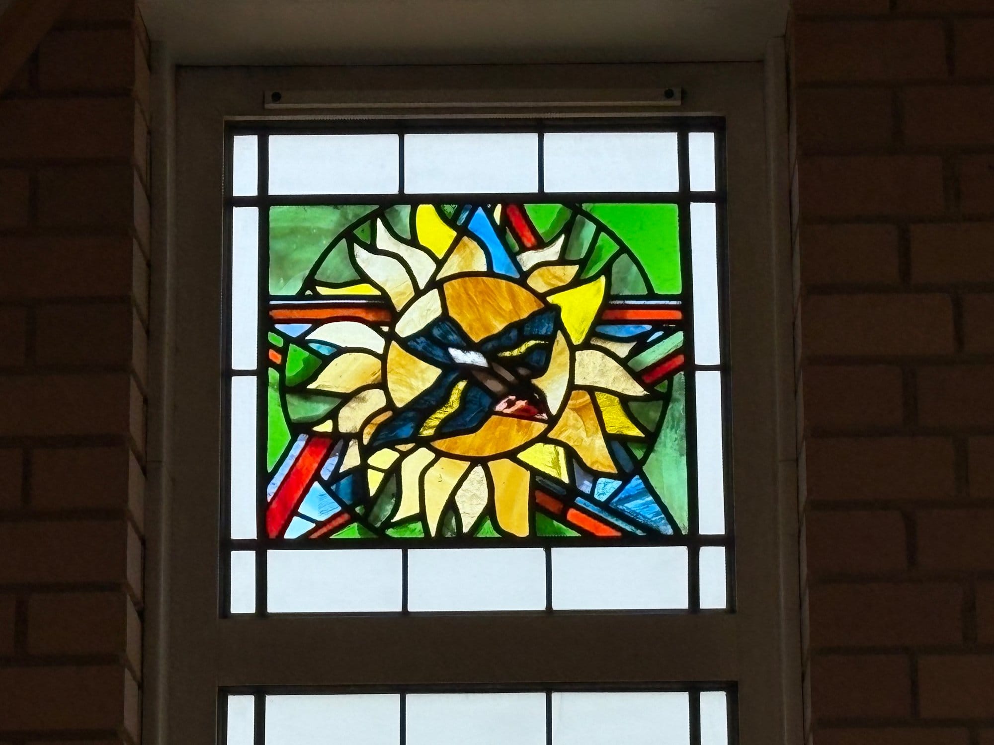 Stained glass panel of a sunflower with a bird at its centre, Northampton