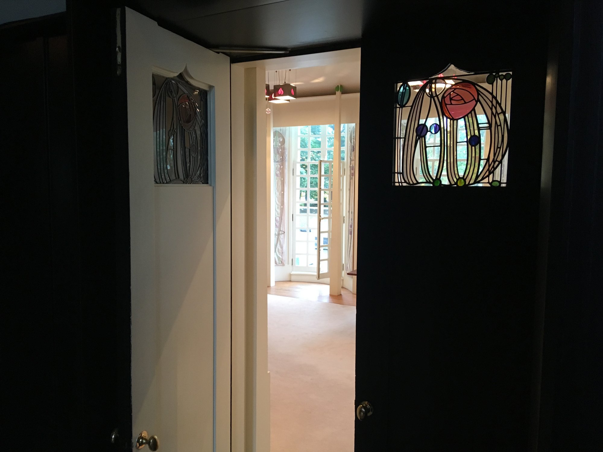 A pair of black doors with small rose panels in leaded glass
