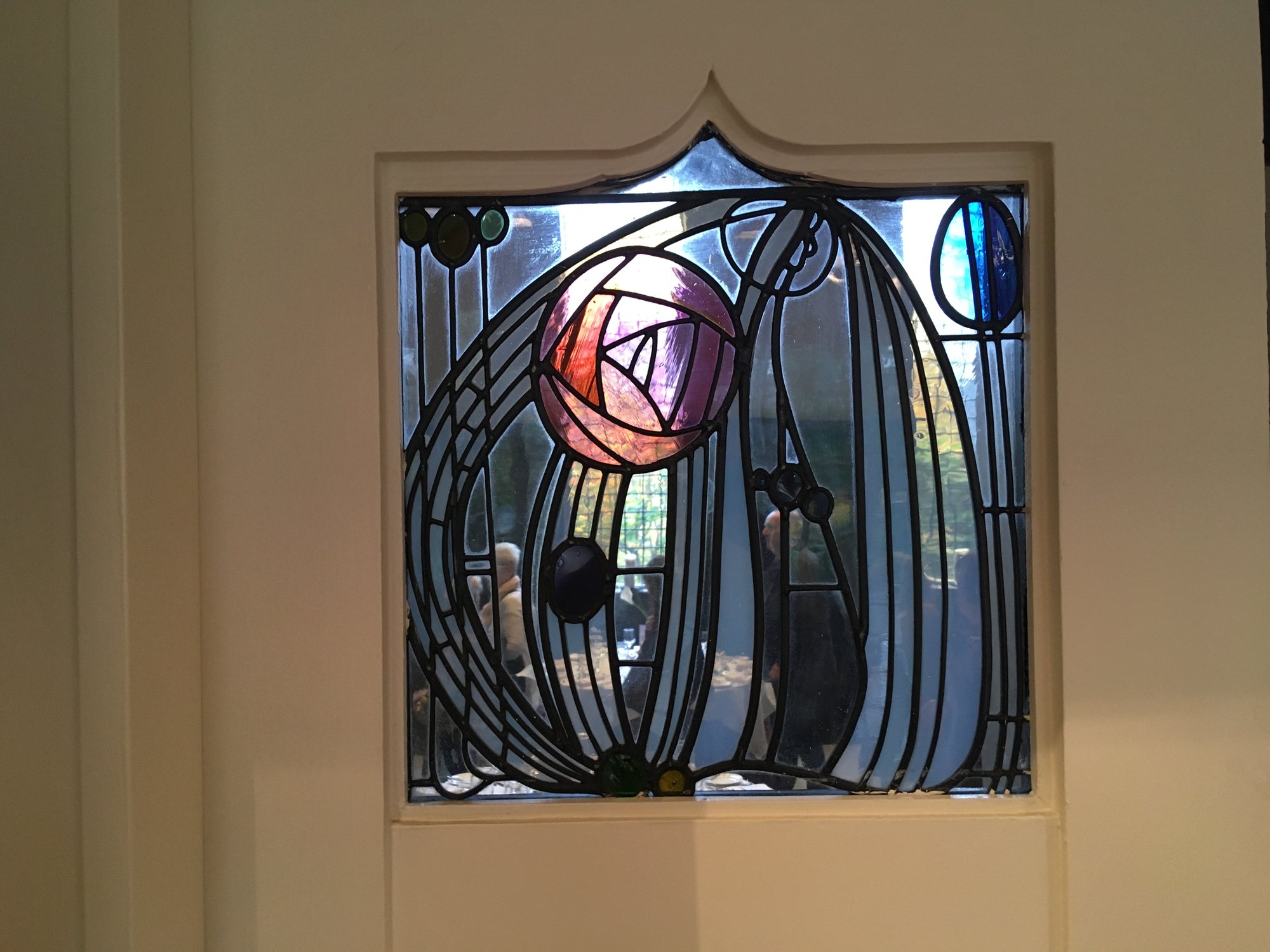 A leaded glass panel with a pink rose and curving lines, set in a door