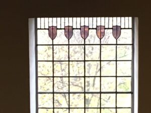 Window with shield shapes above a lead grid at House for an Art Lover