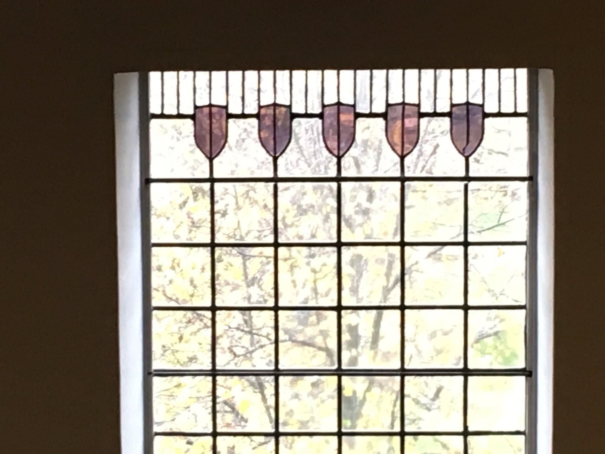 Window with shield shapes above a lead grid at House for an Art Lover