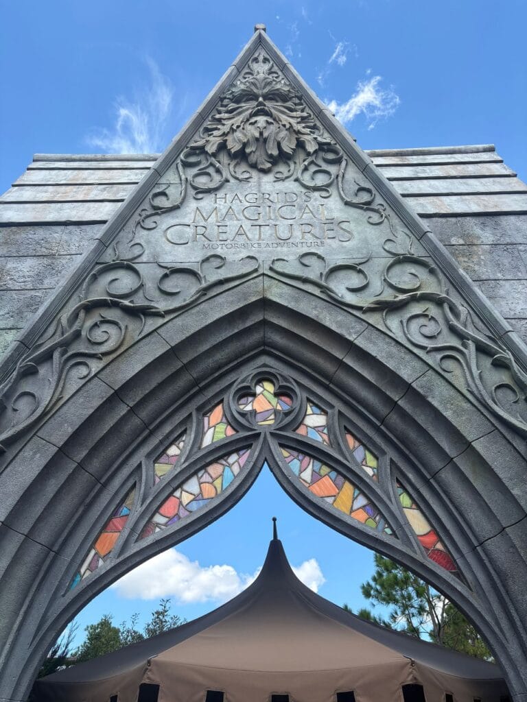 Carved stone gothic arch with coloured stained glass tracery framing a tent roof and blue sky