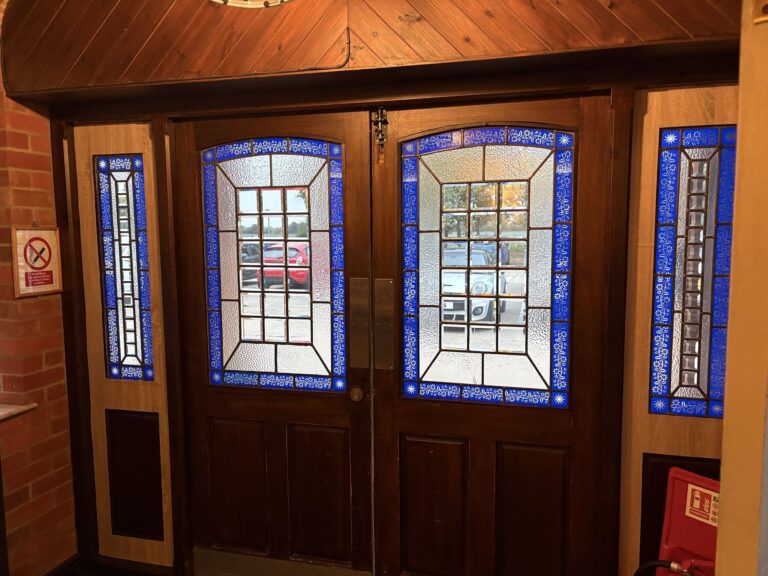 Wooden entrance doors with leaded glass panels edged in blue
