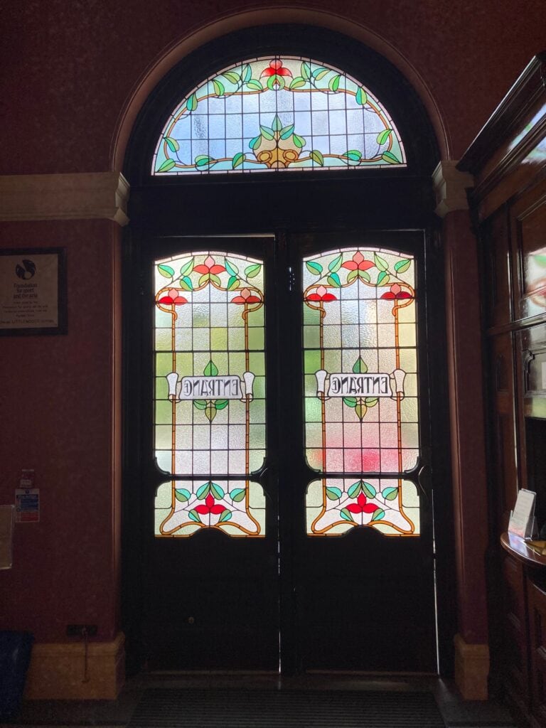 Dark entrance doors with leaded floral panels, ENTRANCE lettering and a green floral fanlight