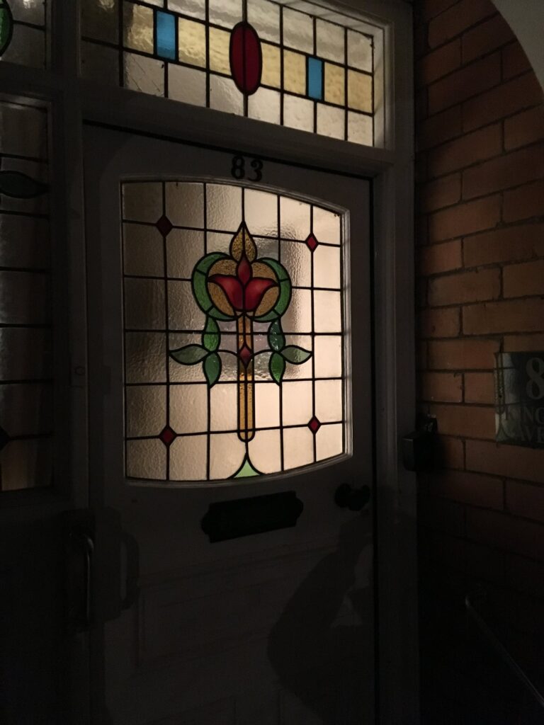 Front door with a leaded light panel showing a red tulip with green leaves and a patterned fanlight above