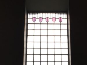 Leaded window with pink shield shaped glass at the top