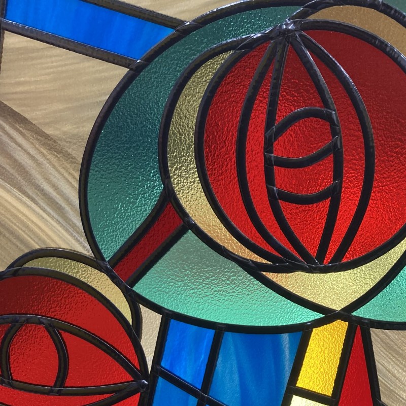 Close-up of a Mackintosh-style rose in overlay glass with coloured glass and black lead lines