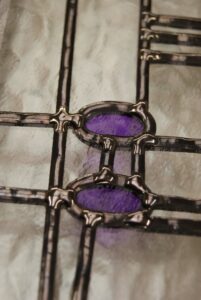 Close view of lead lines and purple glass in a Mackintosh style overlay stained glass panel