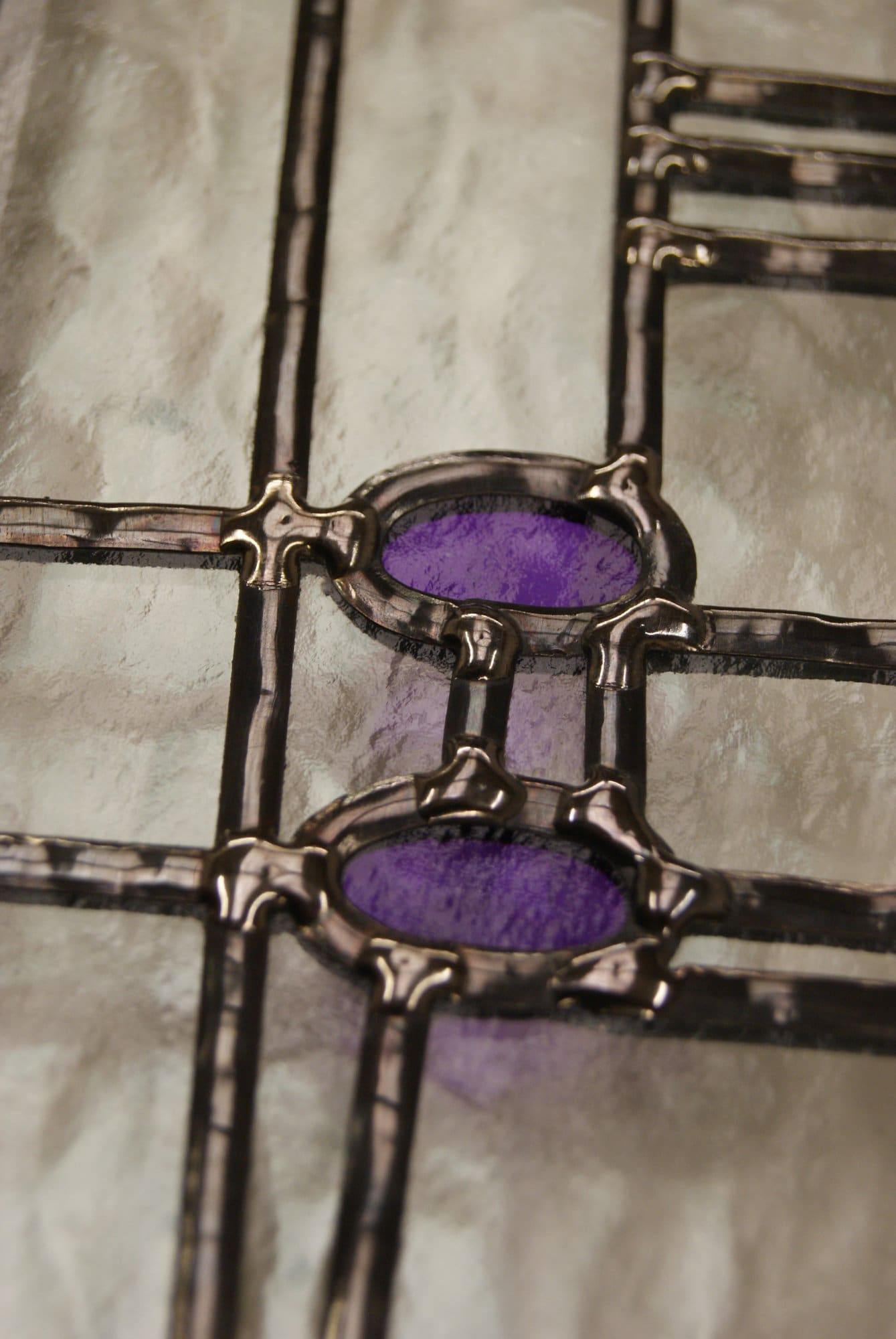 Close view of lead lines and purple glass in a Mackintosh style overlay stained glass panel