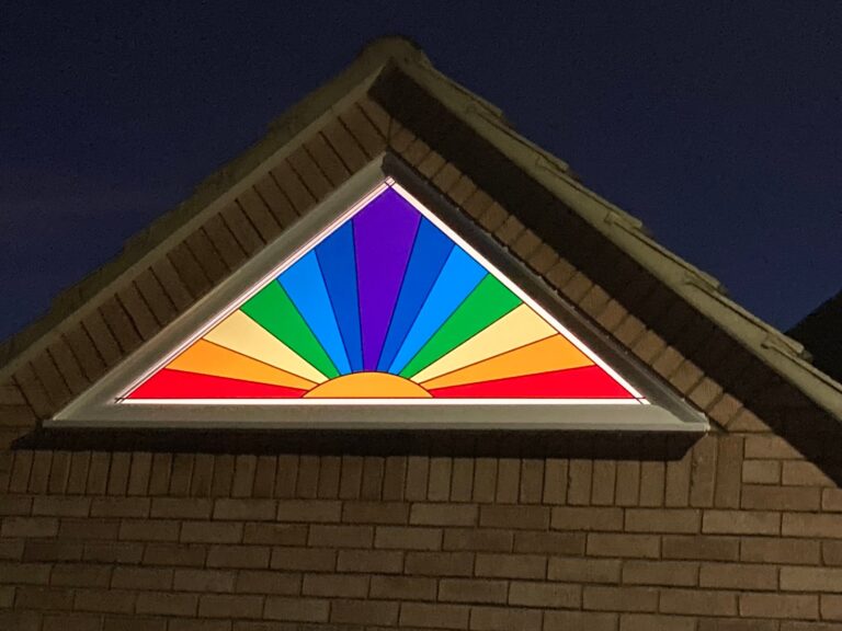Gable window with a rainbow sunburst pattern in overlay stained glass