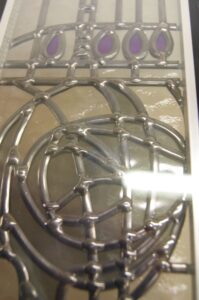 Close view of a Mackintosh rose drawn in lead lines on an overlay stained glass panel
