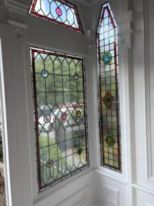 Pointed leaded windows with red border and roundels corner view