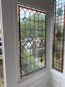 Pointed leaded windows with red border and roundels inside porch
