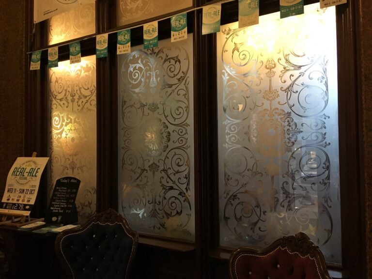Row of etched windows with scrolling leaf patterns in a bar