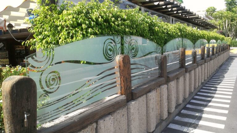 Sandblasted spirals and waves on glass balustrade panels along a walkway