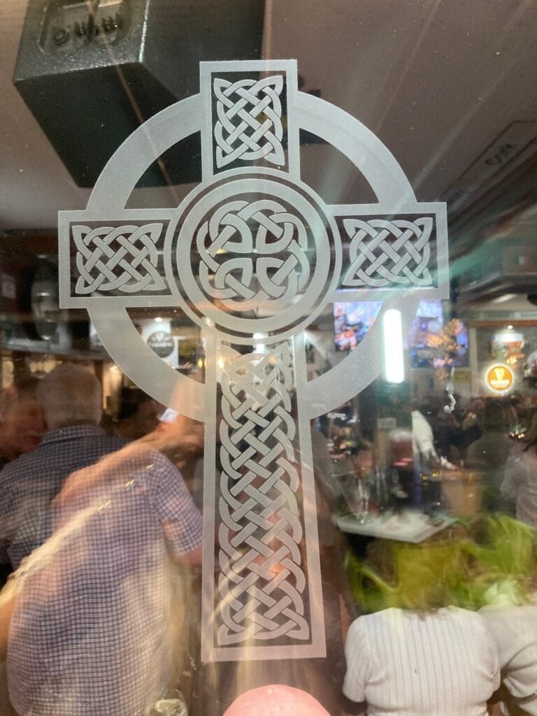 Sandblasted glass panel of a Celtic cross filled with interlaced knotwork