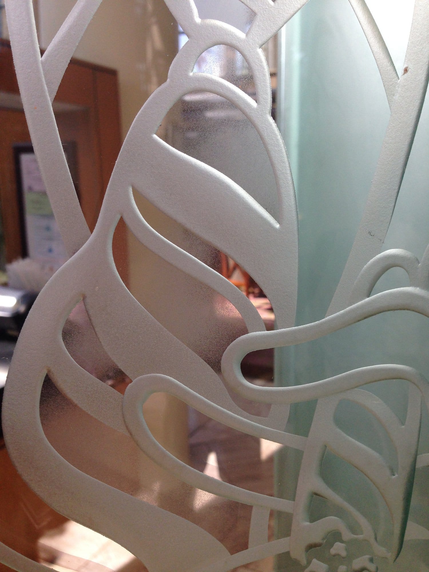 Close view of deeply carved sandblasted glass with large leaf shapes in relief