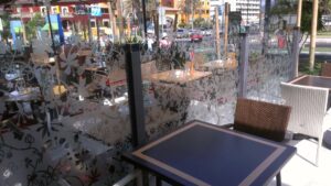 Glass terrace screen sandblasted with a pattern of flowers and leaves around outdoor tables - second view